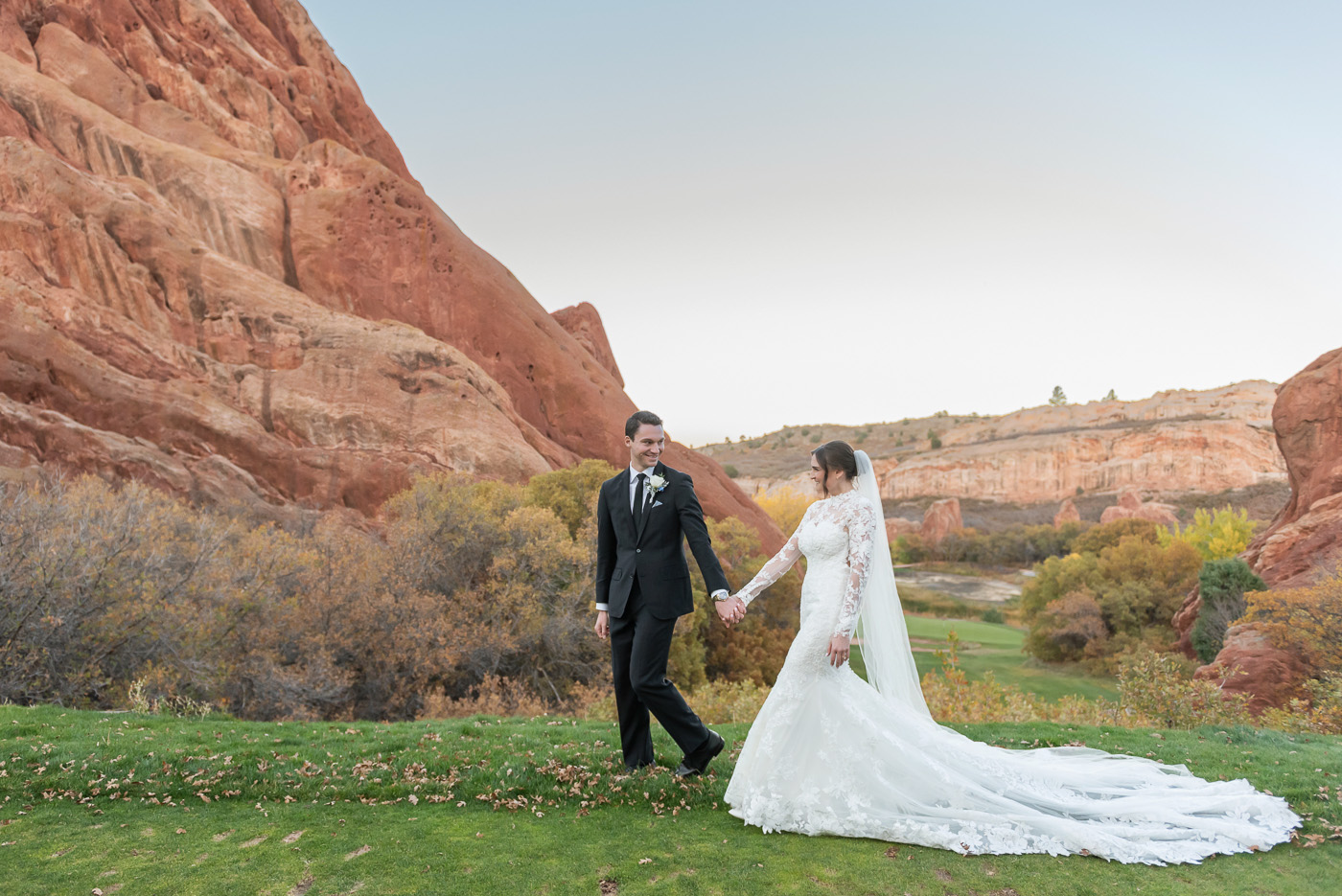 arrowhead wedding photography, colorado, red rocks, bride and groom walk together in front of red rock formations